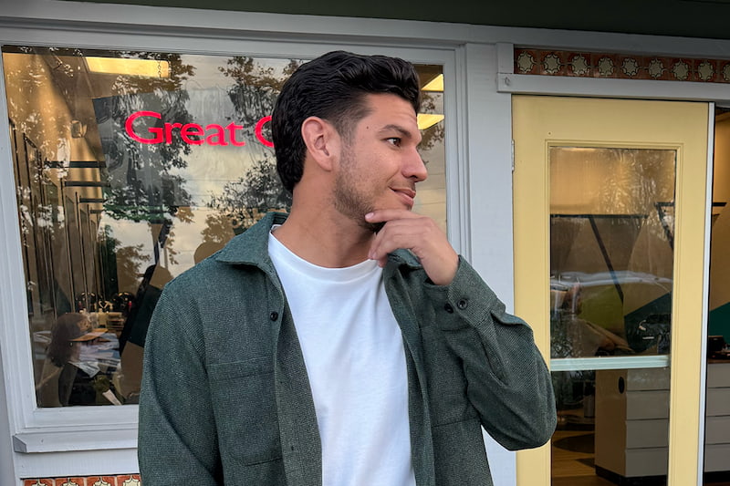 A man with a taper haircut standing outside of a Great Clips salon